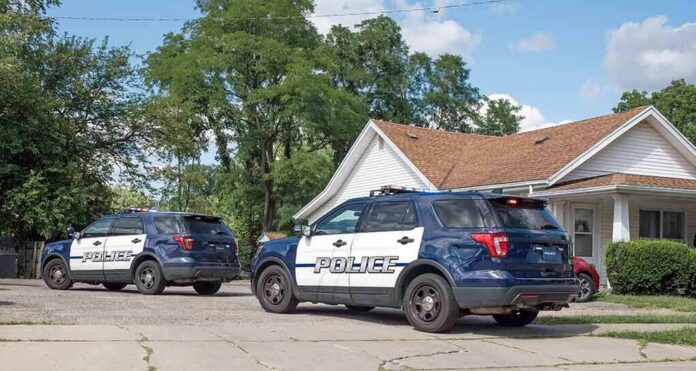 Two police SUVs parked near a suburban house