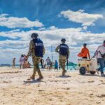 Missing Mom, No Witnesses, Big Questions Beach patrol officers walking among beachgoers on a sunny shoreline