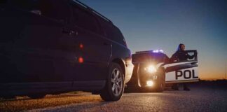 Police officer at patrol car during traffic stop at dusk
