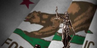 Lady Justice statue with gavel and book before California state flag