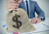 Record Income Meets Sticker Shock Businessperson holding a burlap money bag on a desk