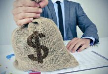 Businessperson holding a burlap money bag on a desk