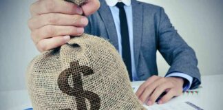 Businessperson holding a burlap money bag on a desk