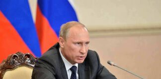 Vladimir Putin speaking at a meeting with documents and a microphone