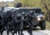 Hybrid Attacks Next? NATO Braces Tactical police team advances from armored vehicle with shields and rifles