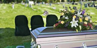 casket with floral arrangement at outdoor graveside service