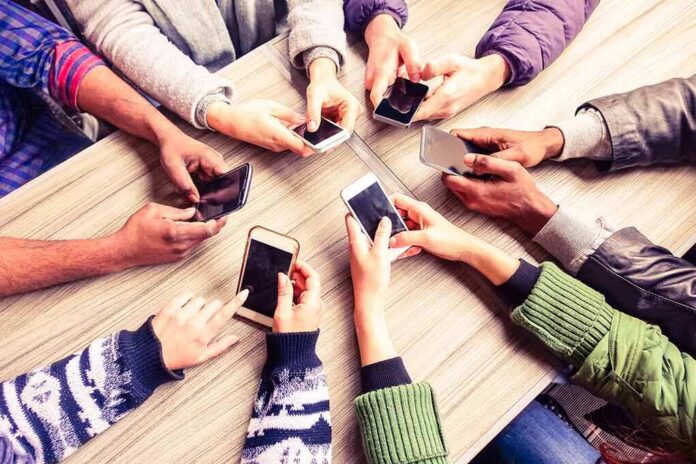 shutterstock_393607117 Hands around a table holding smartphones