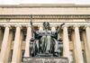 Mystery Heir Claims Rock Uganda Throne Alma Mater statue before a neoclassical library facade
