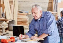 Carpenter marking measurements on plans at a workbench