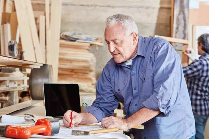 Carpenter marking measurements on plans at a workbench
