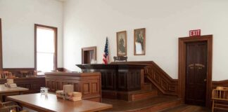Interior of a historic courtroom with wooden furniture and an American flag