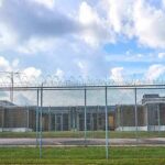 Cop Killer Uproar Freezes Prisoner Release Plan Prison yard behind chain-link and razor wire fence