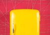 Freezer Corpse Exposes Social Security Hole Yellow retro refrigerator against a pink geometric wall