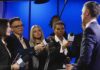 Journalists interview a man in a suit with microphones