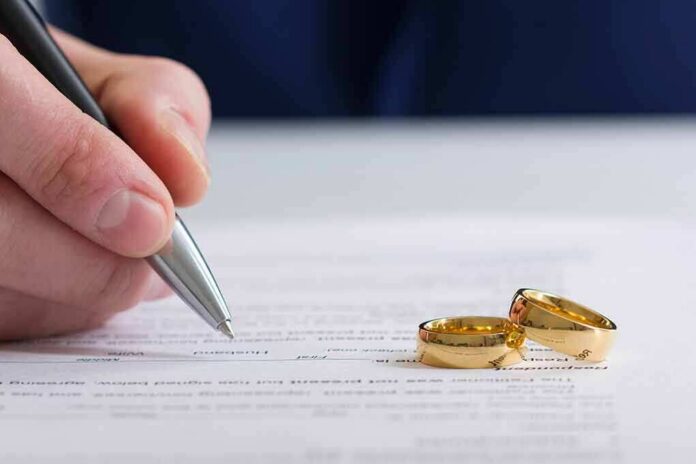 shutterstock_1043592691 Hand signing a document beside two gold wedding rings