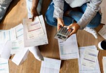 People sitting on floor calculating bills with a calculator