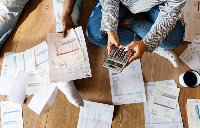 People sitting on floor calculating bills with a calculator