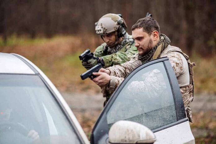 shutterstock_1083084497 Two armed men in tactical gear aiming pistols at a car
