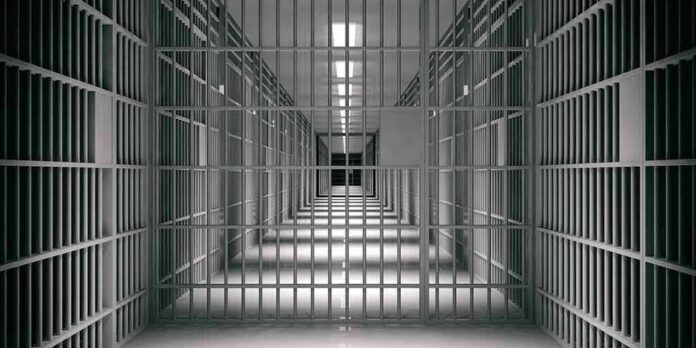 shutterstock_1118920109 empty prison corridor with barred cells