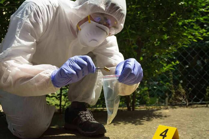 shutterstock_1157300710 Forensic technician collects bullet casing at outdoor crime scene