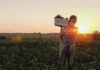 Farmer carrying a crate of vegetables at sunset in a field