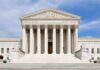 High Court Showdown: Who Gets Locked In? Front view of the Supreme Court building with large columns and steps under a blue sky