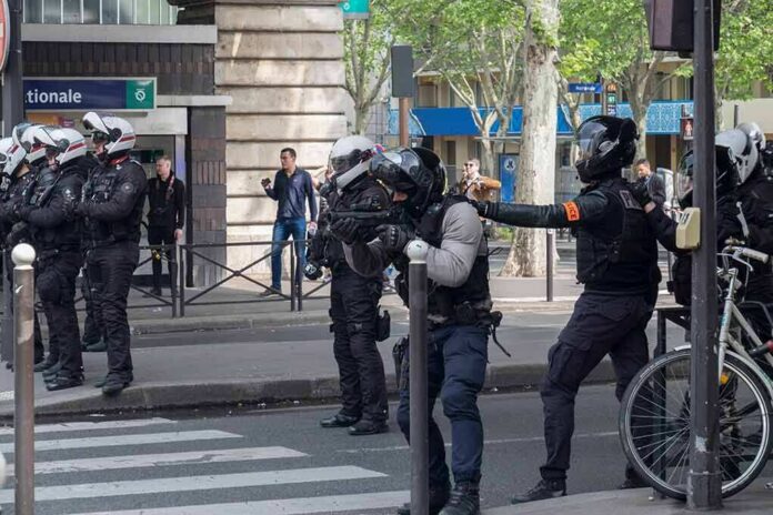 shutterstock_1392139244 Riot police in helmets line a city street during an operation