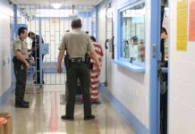 Corrections officers escort an inmate in a jail hallway