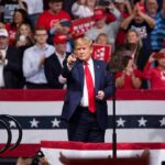 Trump Blitz Hits Nebraska – What’s Brewing? Donald Trump points from a rally stage; Rudi Koertzen and Bear Pascoe are in the crowd