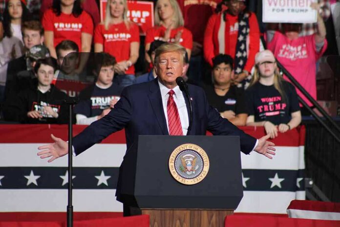 shutterstock_1662925921 Donald Trump speaks at a rally podium; Frida Öhrn and Charly Black are in the crowd