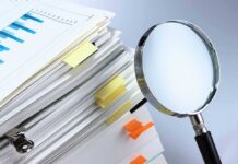 Stack of documents with a magnifying glass beside it