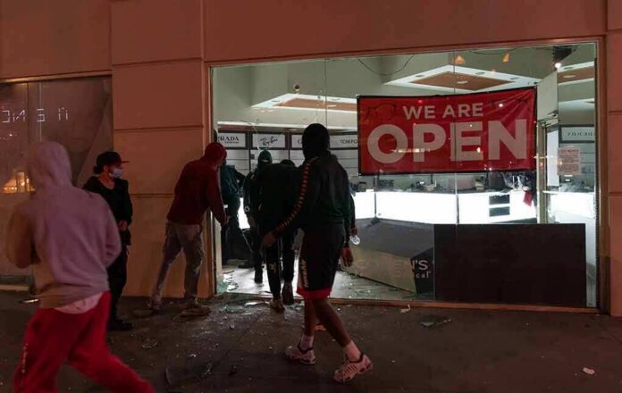 People outside a storefront with broken glass at night