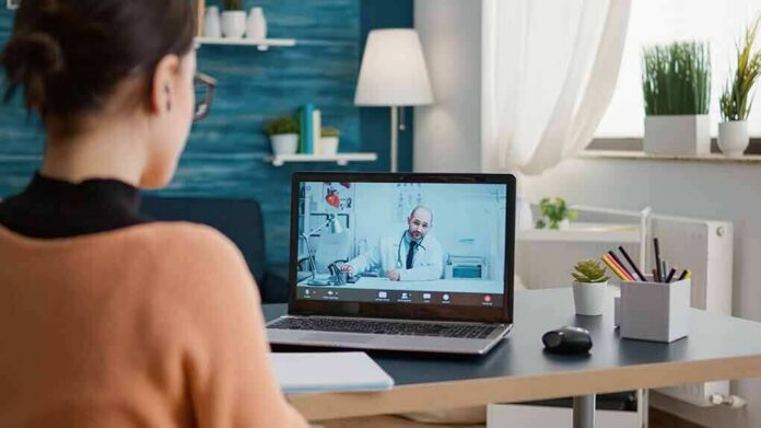 Woman on laptop having video call with doctor in home office